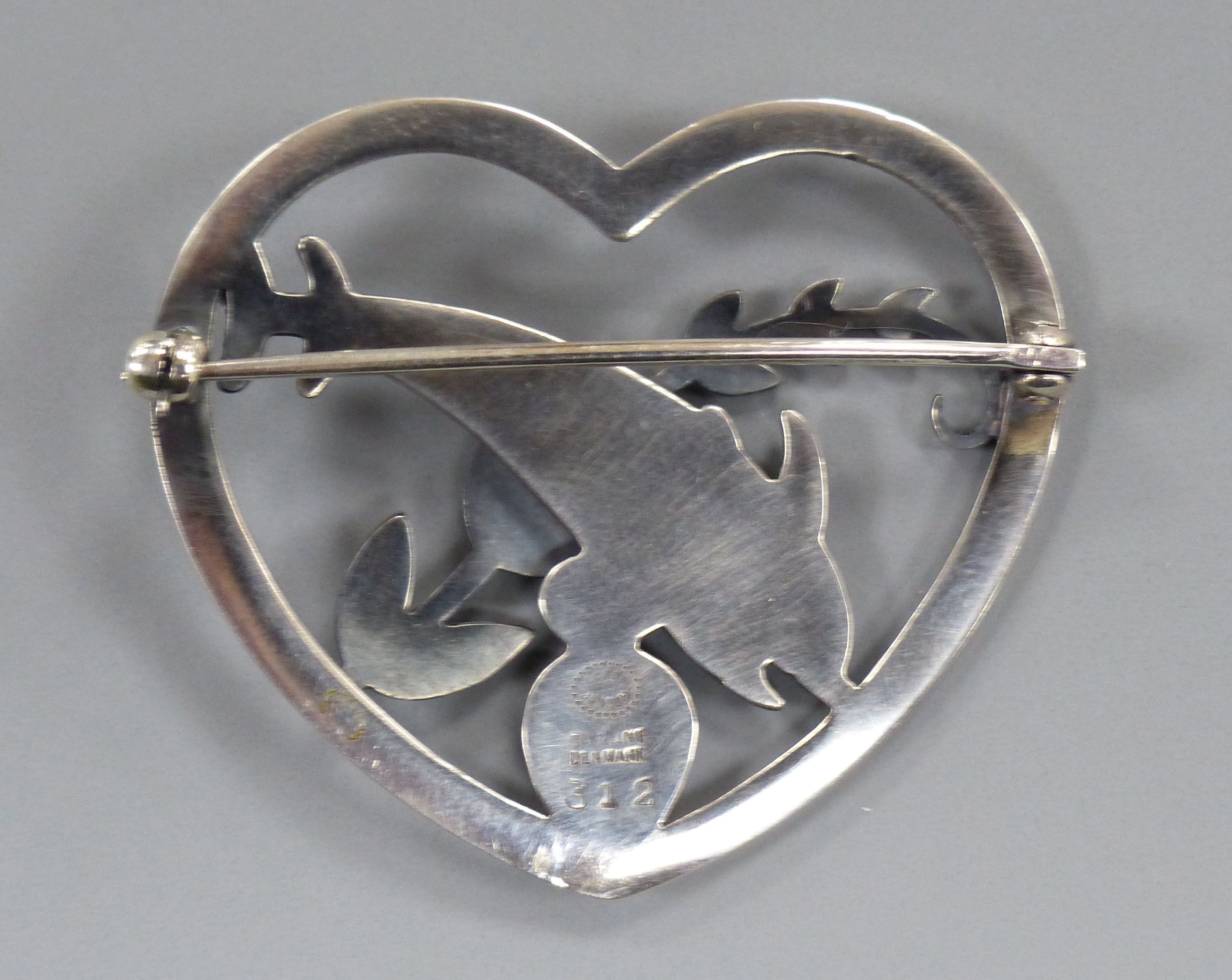 A Georg Jensen sterling heart shaped brooch, depicting twin leaping dolphins with frond, no. 312, 41mm.